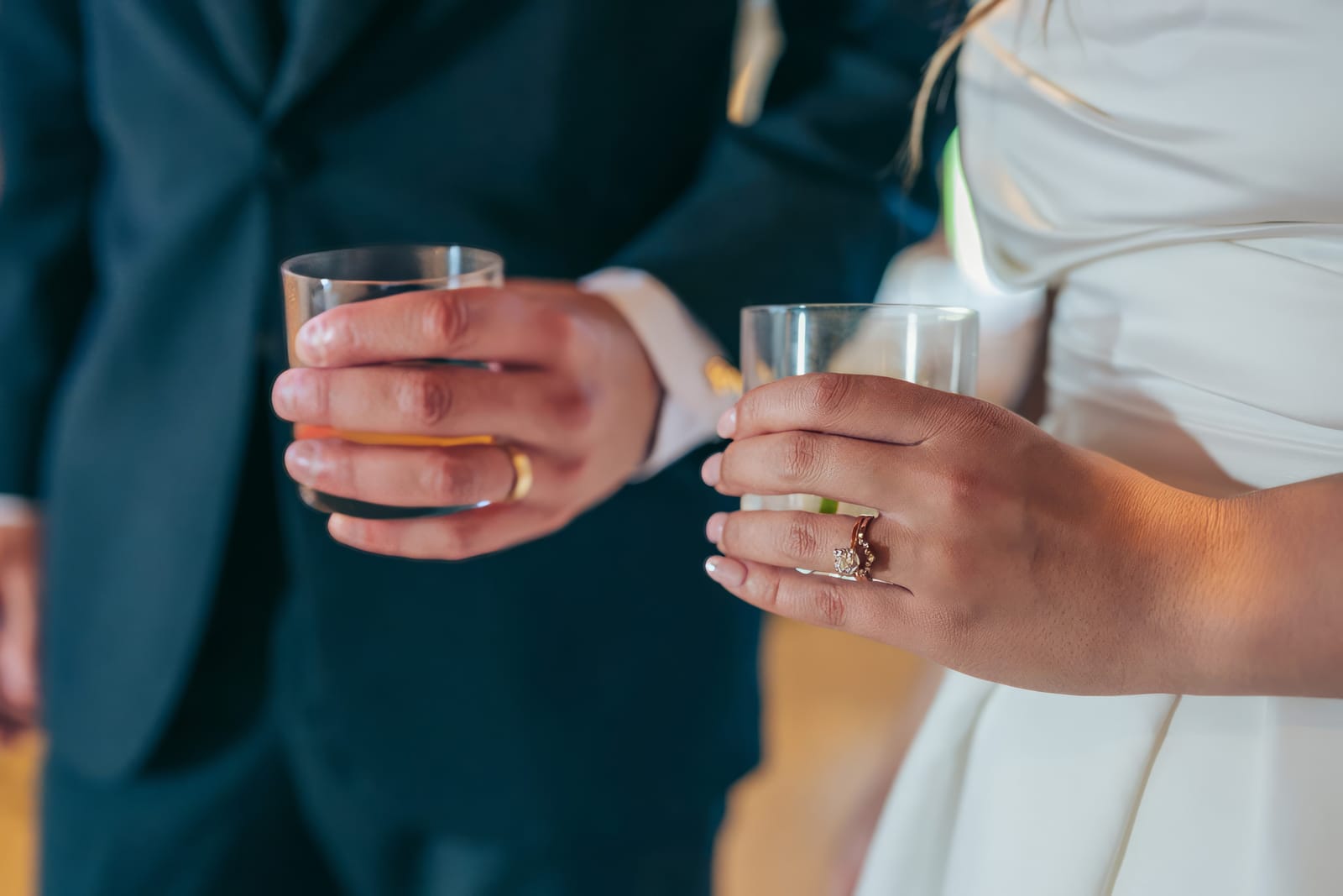 Close-up of Carol and Eric's hands holding drinks, rings visible