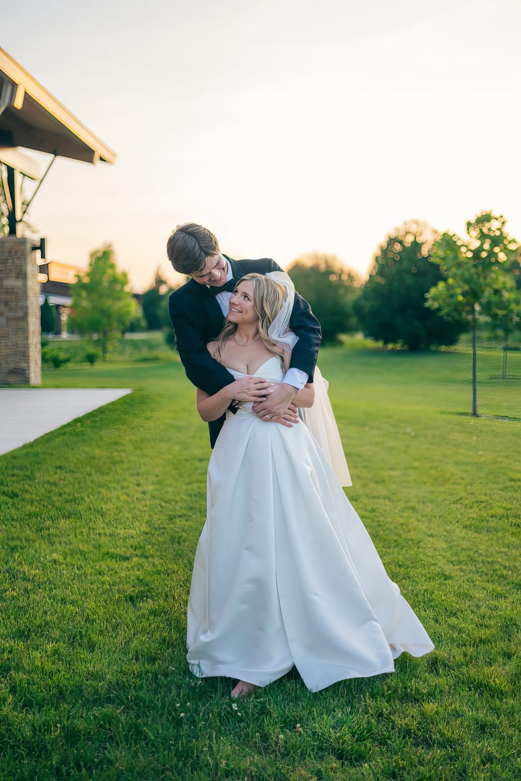 Carol and Eric embracing on the lawn at golden hour