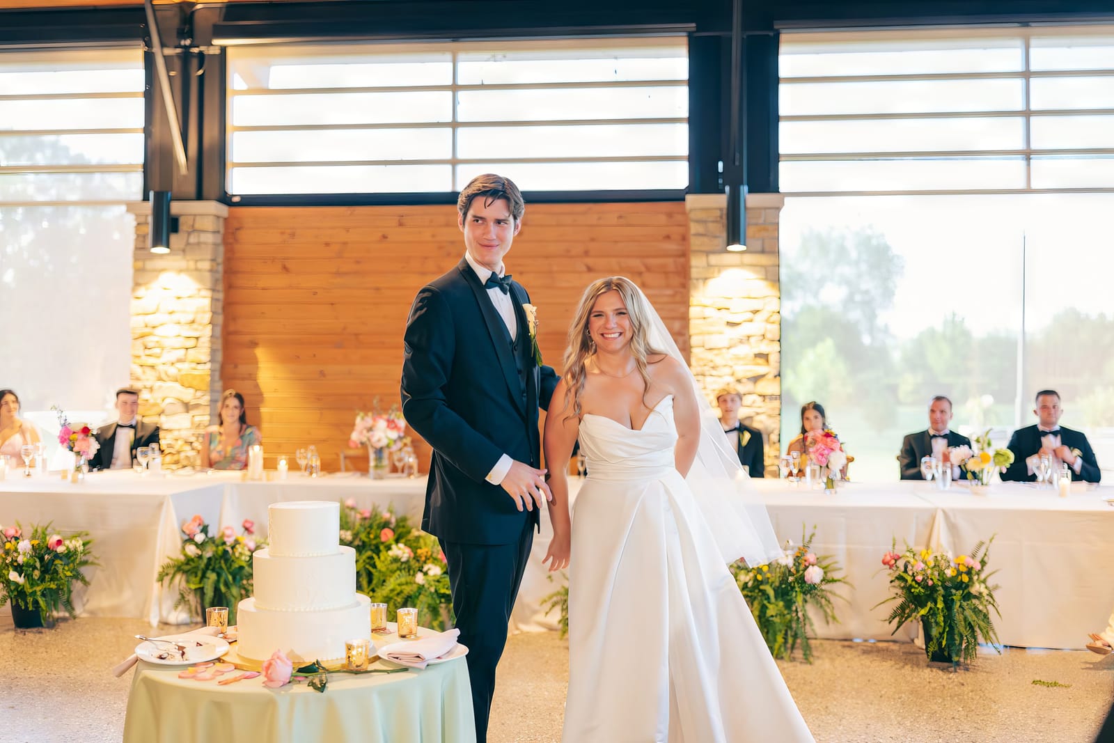 Carol and Eric entering the reception in front of guests and the wedding cake